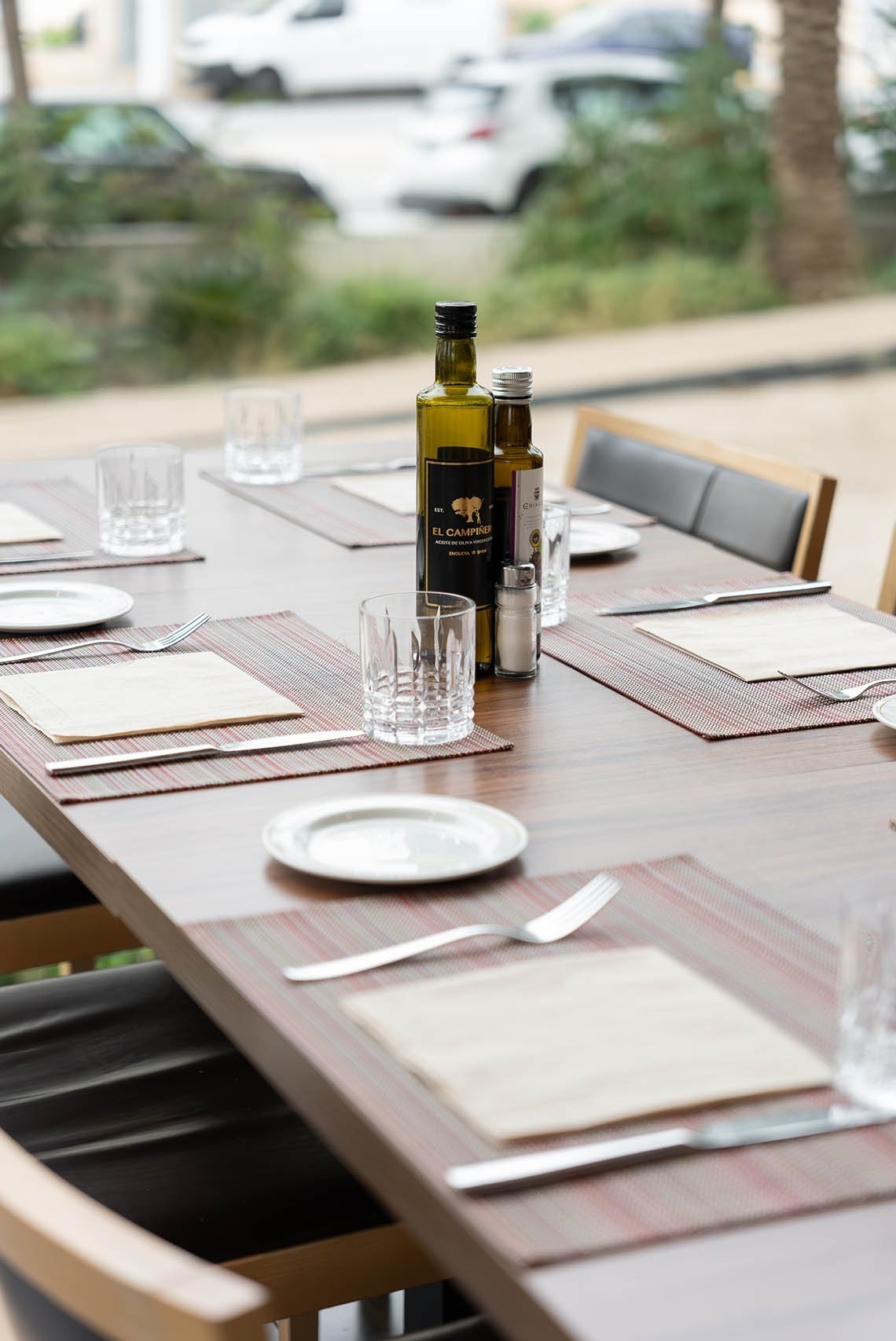 una mesa con platos y cubiertos y una botella de aceite de oliva