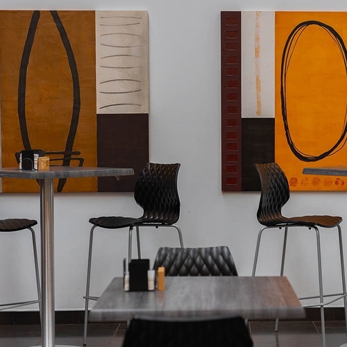 una habitación con mesas y sillas y dos pinturas en la pared