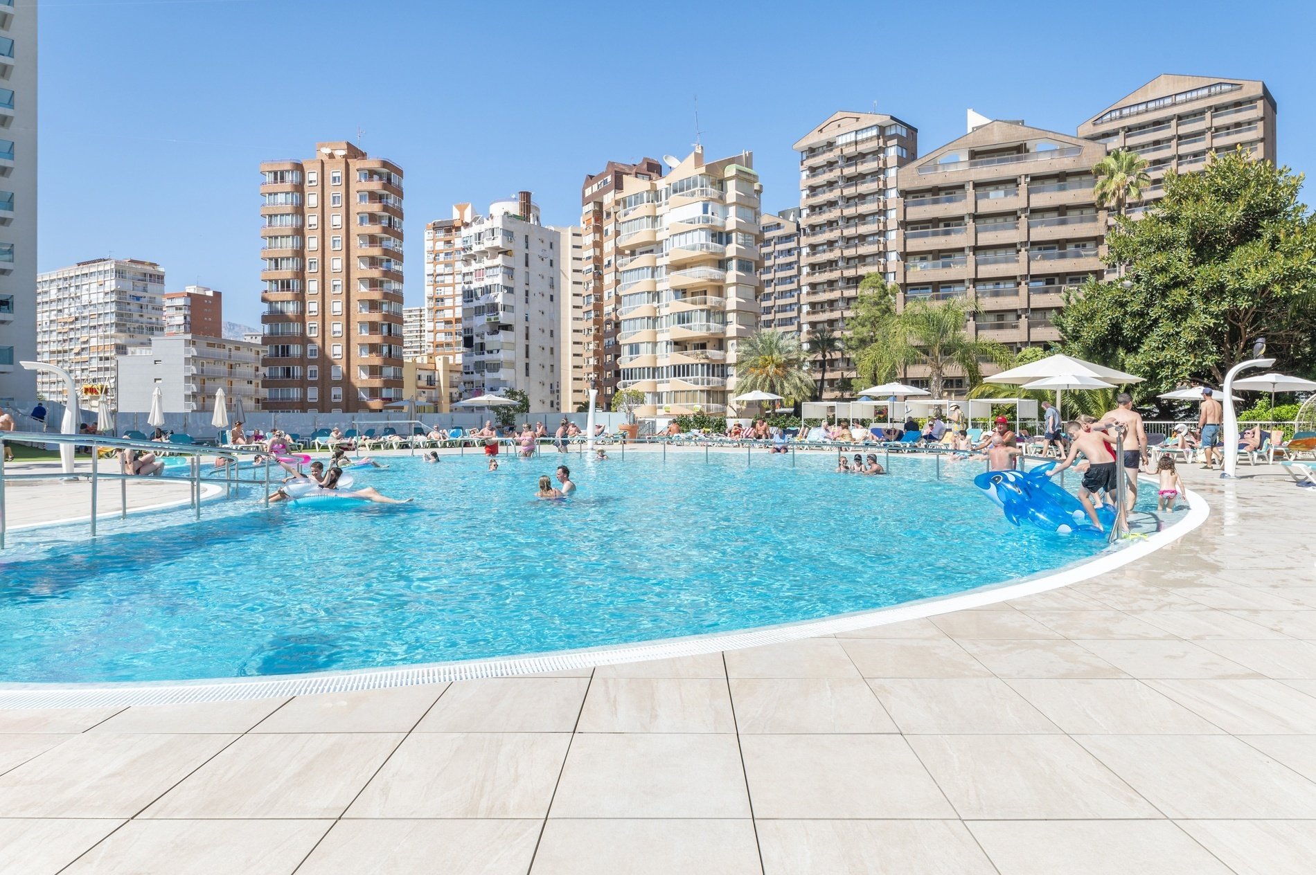 un grupo de personas se divierten en una piscina rodeada de edificios