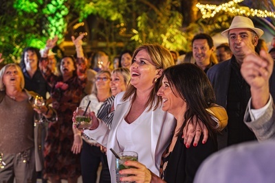 a group of people are dancing at a party and one woman is holding a drink - 