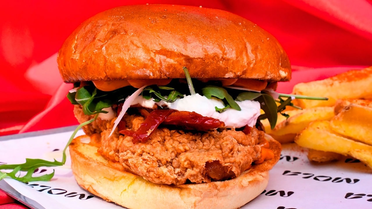 a fried chicken sandwich sits on a paper that says flow