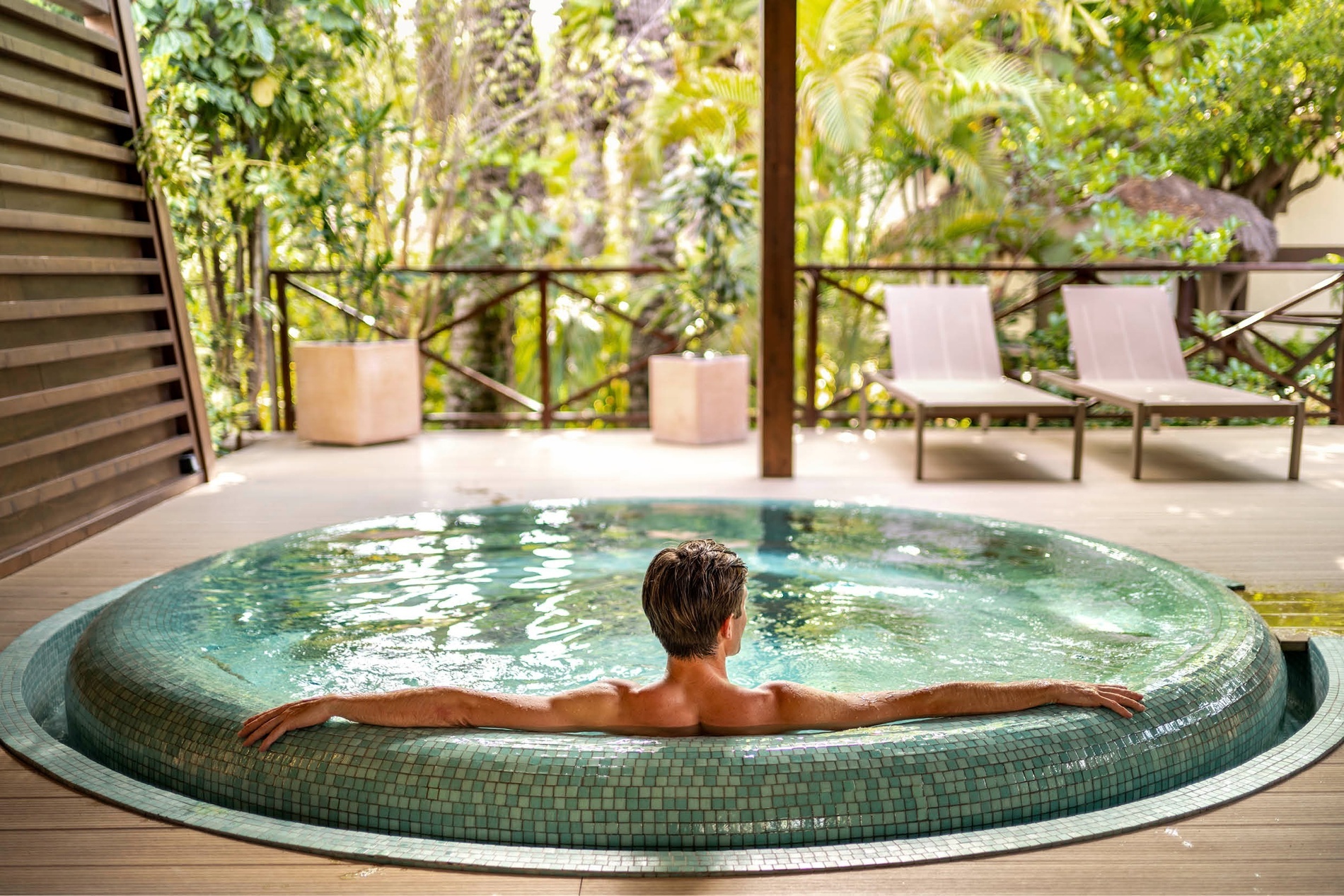 a man sits in a hot tub with his arms outstretched