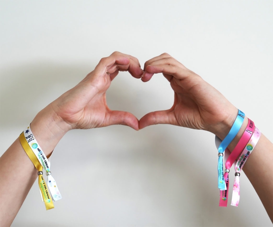a person making a heart shape with their hands wearing a wristband that says 