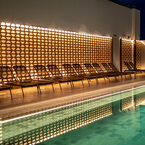 una fila de sillas junto a una piscina en la noche