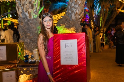 una mujer con un vestido rosa sostiene una caja roja que dice lote 2 - 