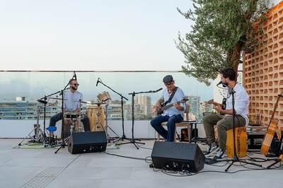 tres hombres están tocando instrumentos musicales en un escenario y uno de ellos lleva un sombrero - 