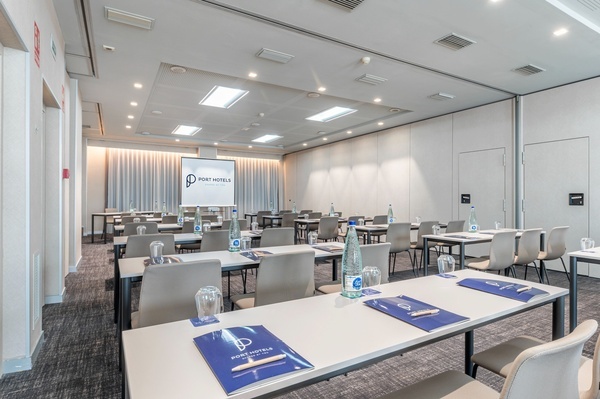 una sala de conferencias con mesas y sillas y una pantalla que dice port hotels