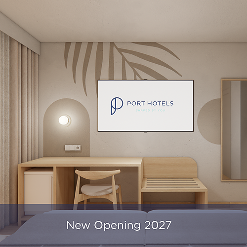 Modern hotel room with desk, TV, and mirror. Port Hotels: Corporativa opening 2027.