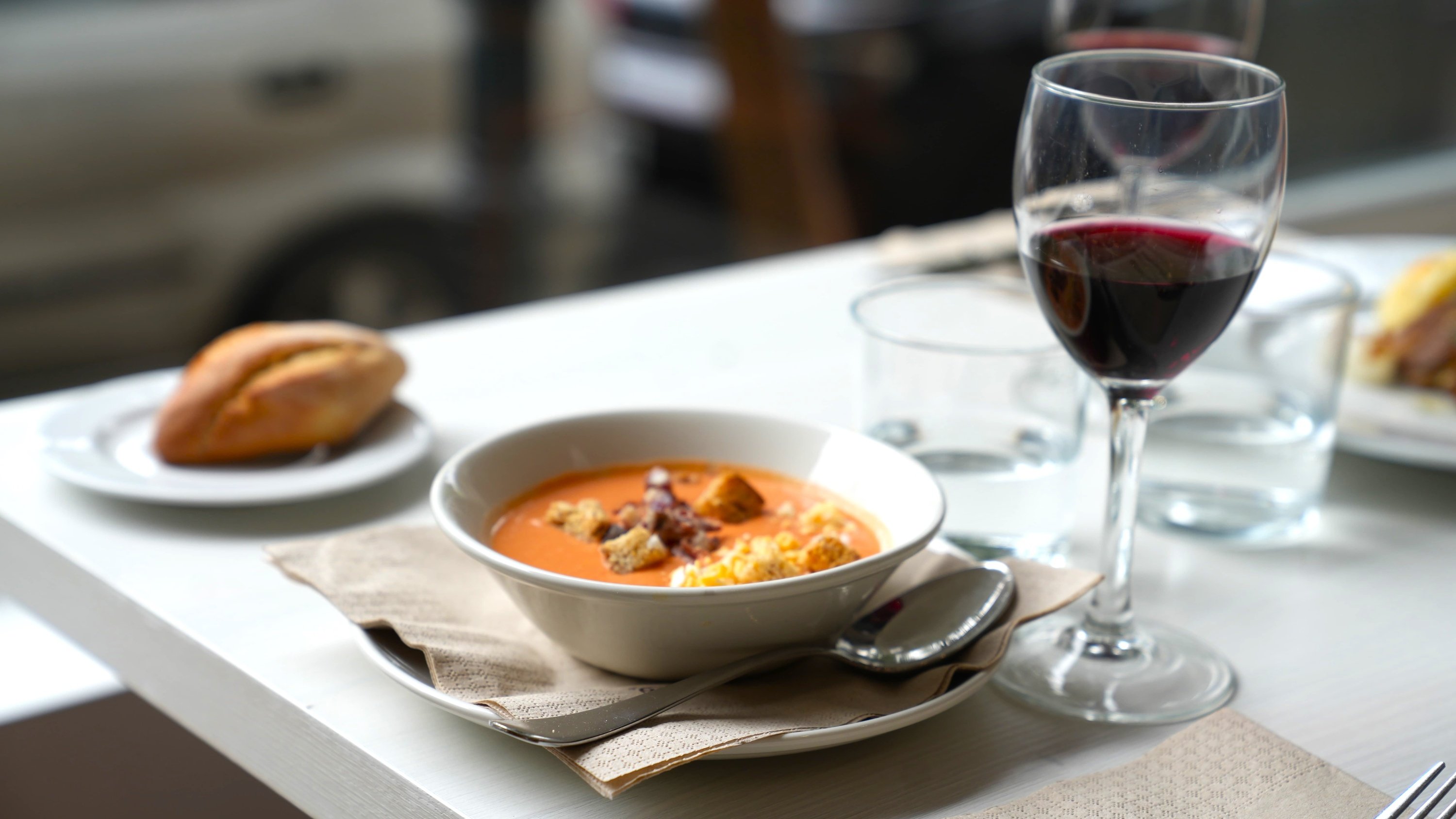 a bowl of soup and a glass of wine on a table