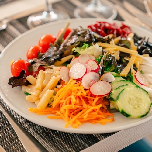 a plate of salad with tomatoes carrots radishes and cucumbers