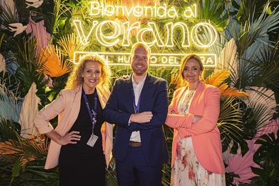 three people pose in front of a sign that says bienvenido al verano - 