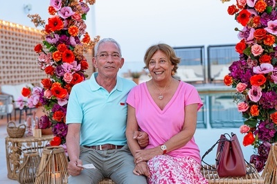 a man and woman are posing for a picture in front of flowers - 