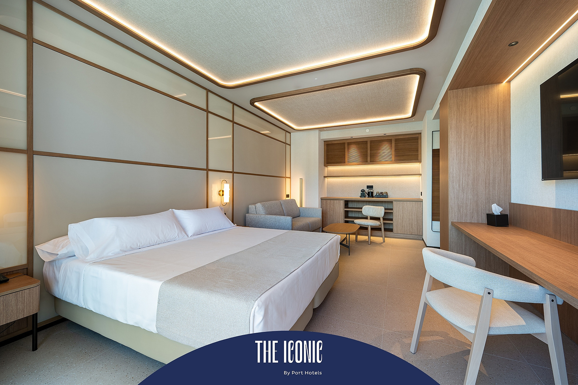Acogedora habitación de hotel con cama, sofá y escritorio. Port Hotels: Corporativa.