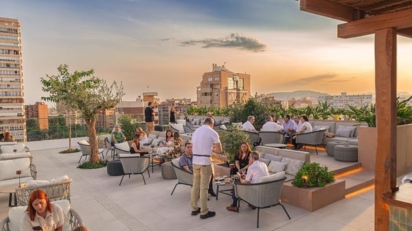 un grupo de personas están sentadas en sillas y mesas en un patio al aire libre