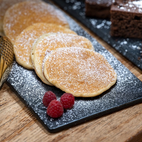 a tray of pancakes with raspberries and powdered sugar