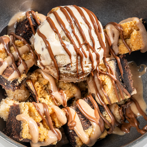 un tazón de brownies cubiertos de helado y chocolate
