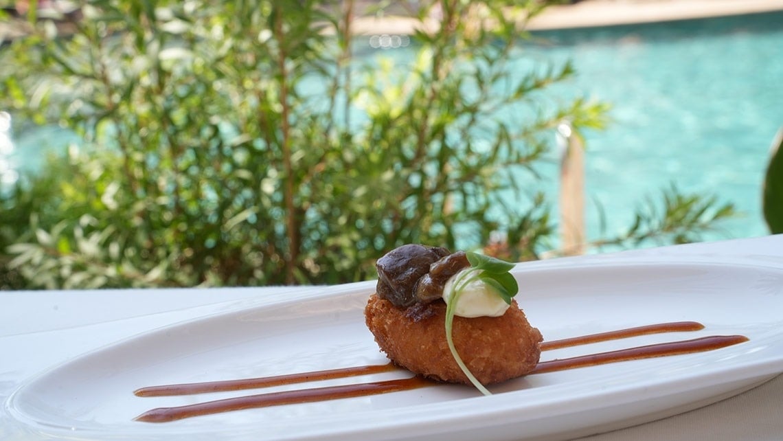 un primer plano de un plato de comida con una piscina en el fondo