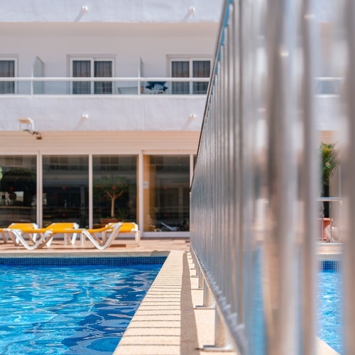 una piscina con sillas amarillas y un edificio en el fondo