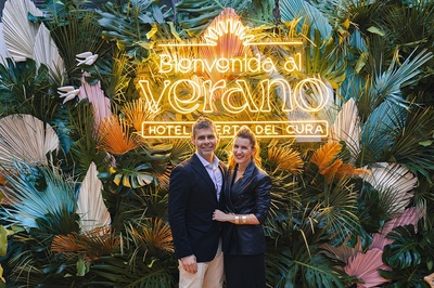 a man and woman pose in front of a sign that says bienvenido al verano - 