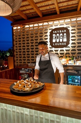 a man prepares food in front of a sign that says skybar boga lounge - 