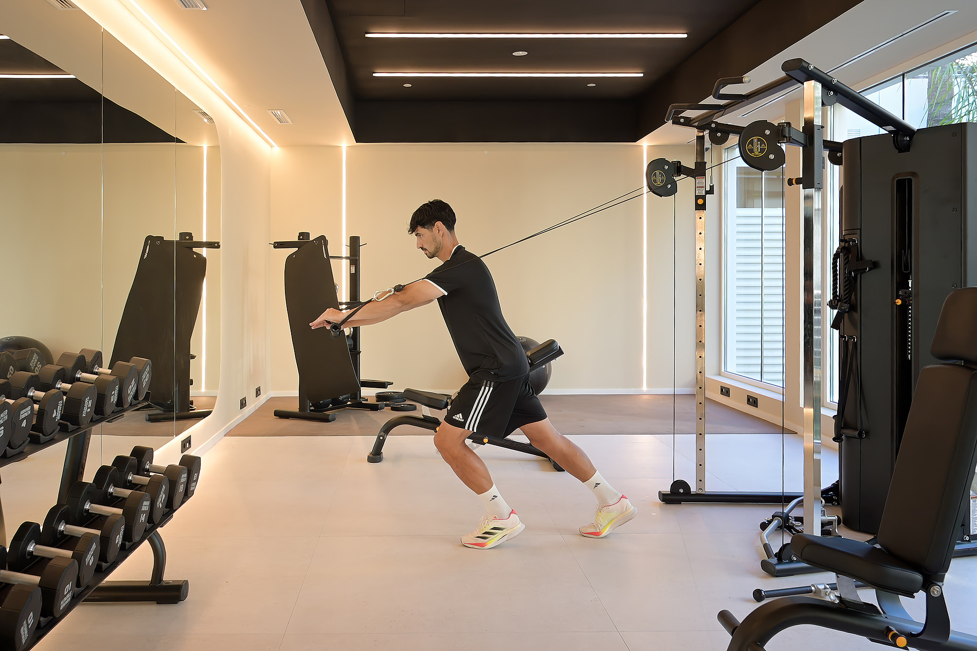 Hombre entrenando en gimnasio de hotel con Bienestar Port Benidorm Hotel & Spa | Port Hotels | Web Oficial, pesas y máquinas.