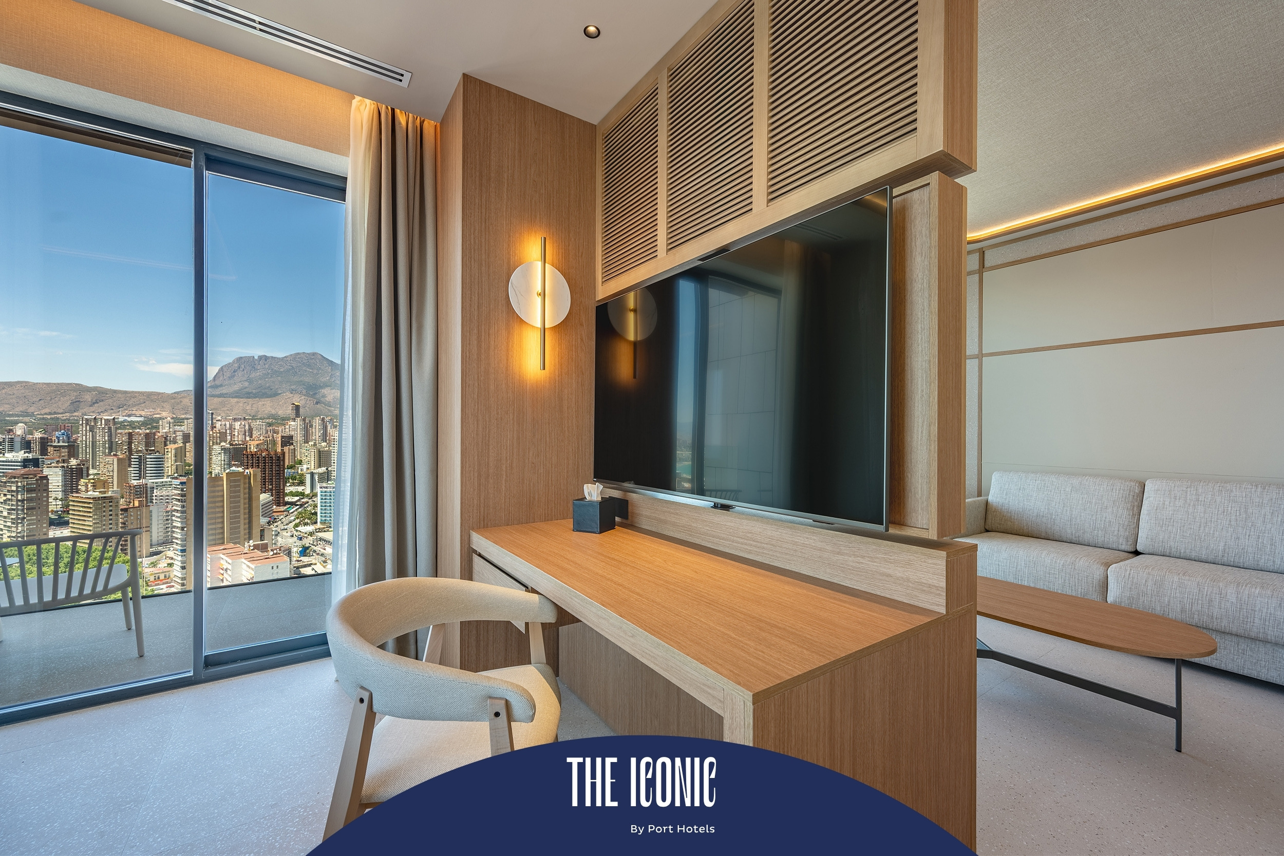 Elegante habitación de hotel con vista panorámica, escritorio de madera, sofá y TV. La estadía perfecta en Port Hotels: Corporativa.