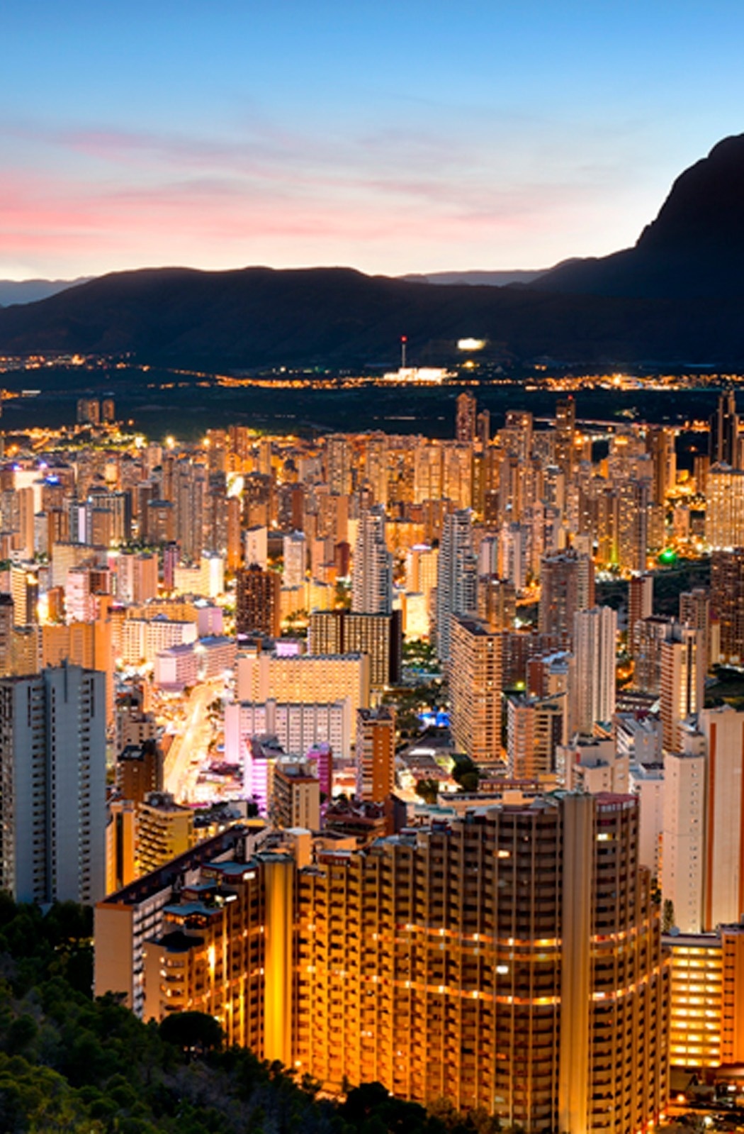 Impresionante skyline urbano al anochecer con rascacielos iluminados. Descubre tu estancia perfecta.