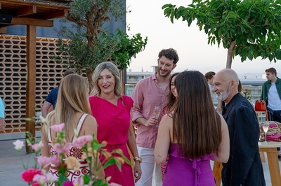 a group of people are standing around talking and one woman is wearing a pink top - 