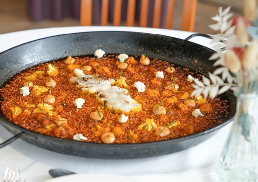 a pan of rice with shrimp and cauliflower on a table