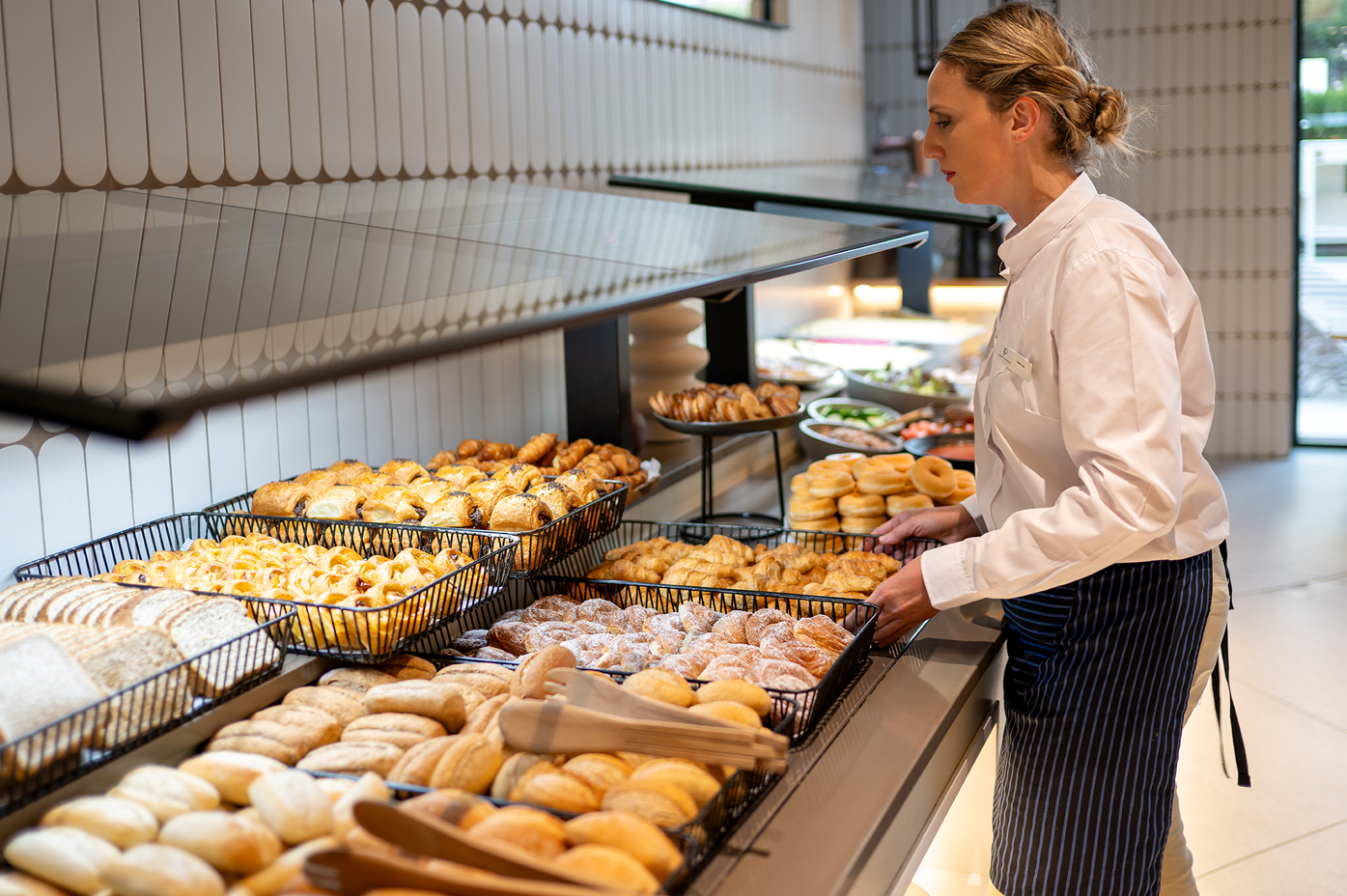 una mujer se sienta frente a un buffet de panadería