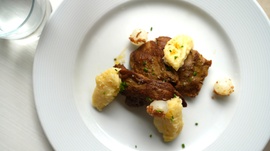 un plato blanco con carne y puré de papas