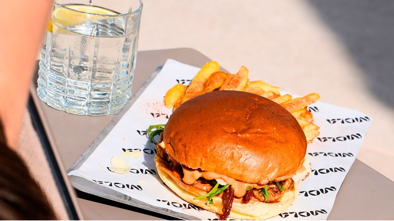 a hamburger and french fries on a plate with a glass of water