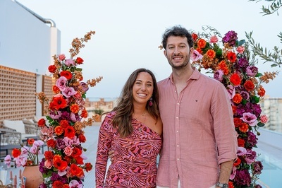 a man and a woman are posing for a picture in front of flowers - 