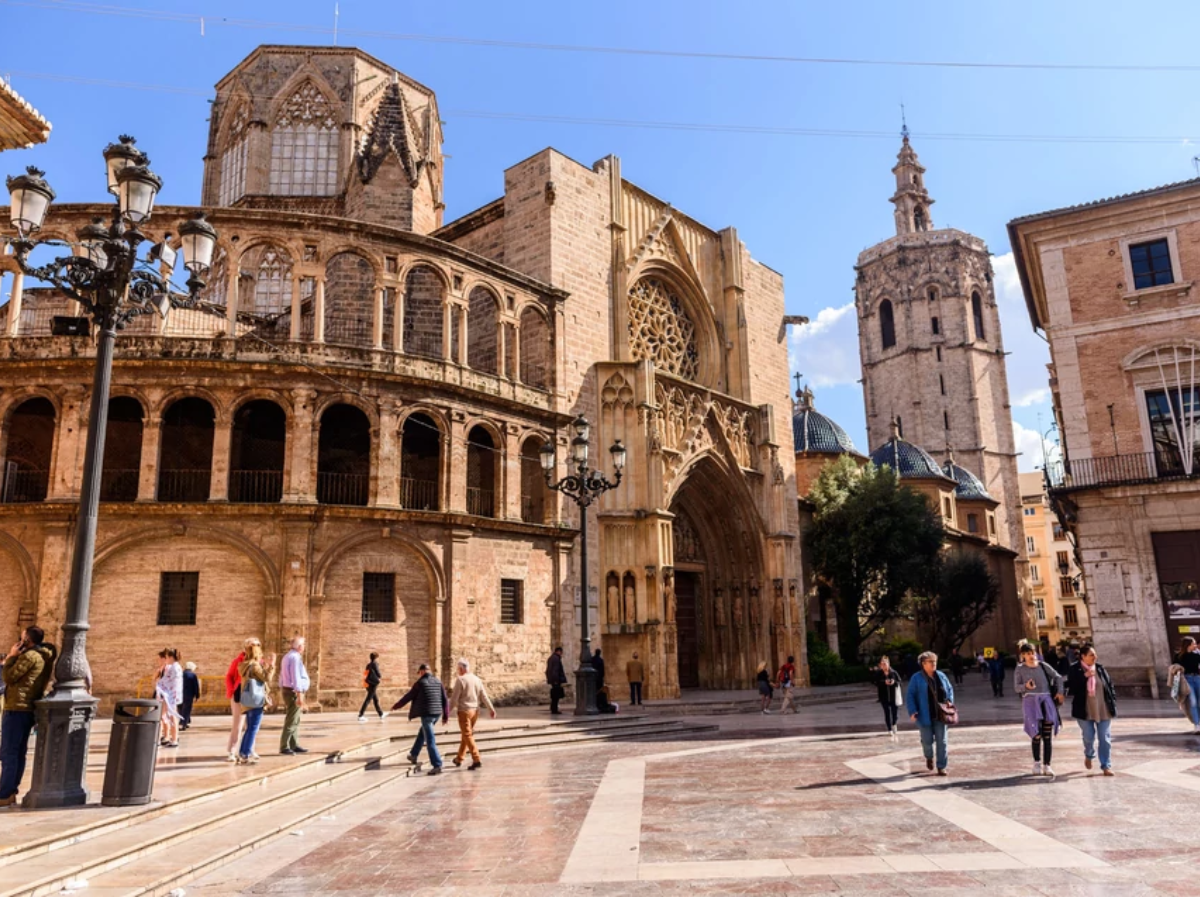 un grupo de personas camina por una plaza frente a una catedral