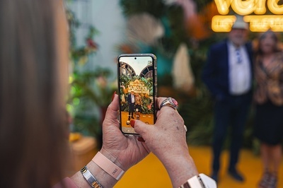 a person taking a picture of a man with a sign that says ' tropical paradise ' on it - 