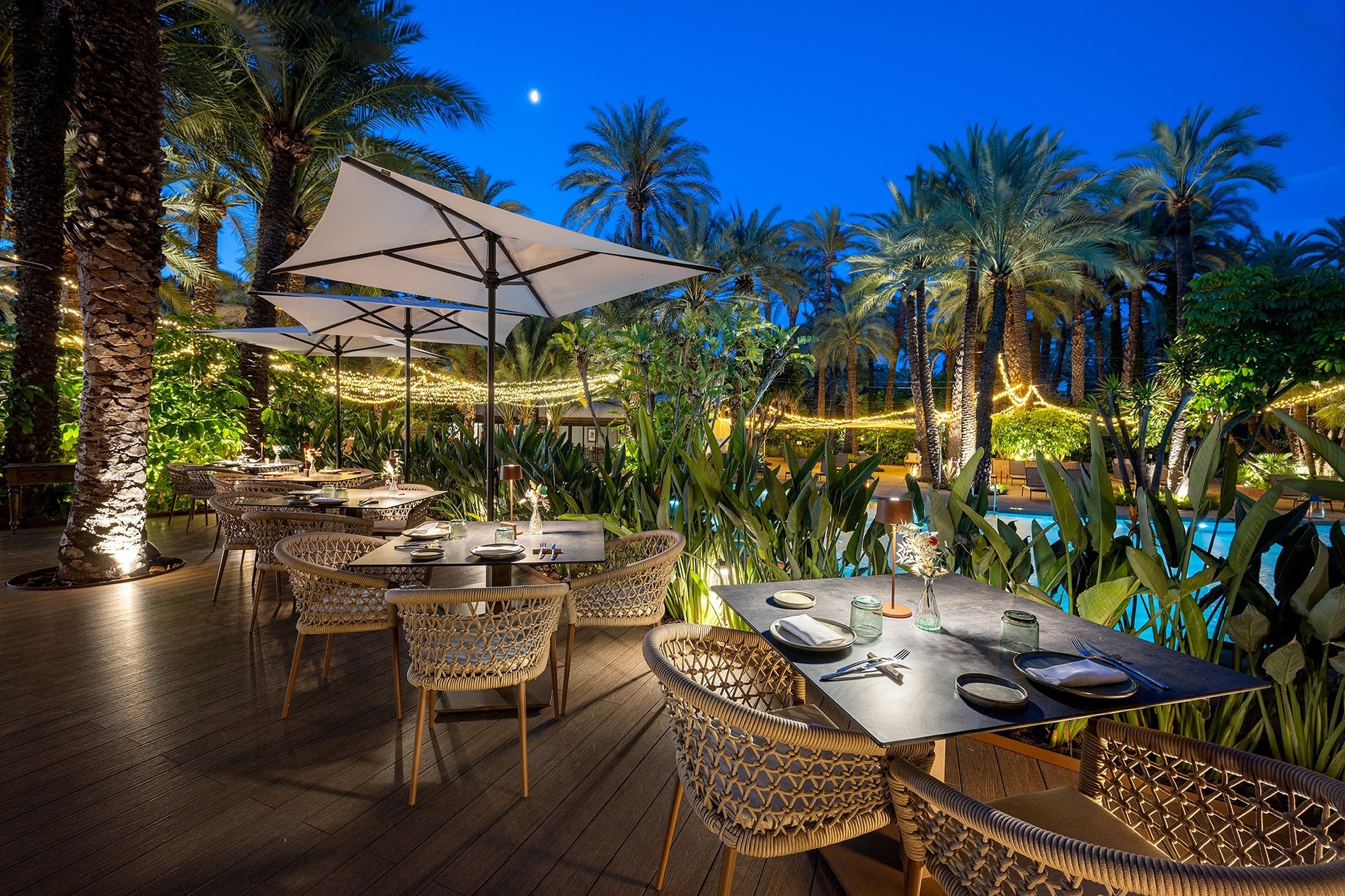 a patio with tables and chairs and umbrellas at night
