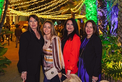 four women are posing for a picture in front of a string of lights - 