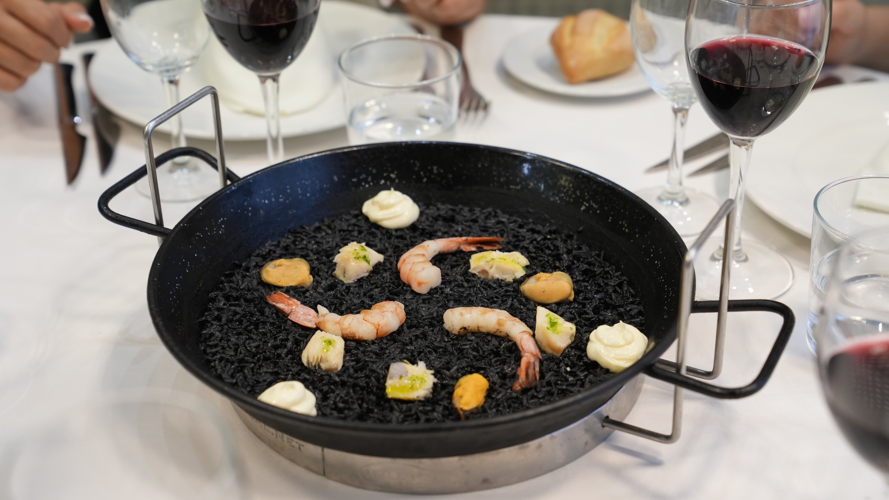 a pan filled with black rice and shrimp sits on a table