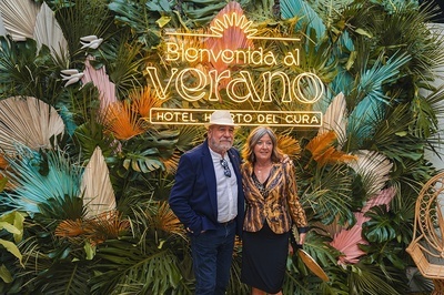 a man and woman standing in front of a sign that says bienvenido al verano - 