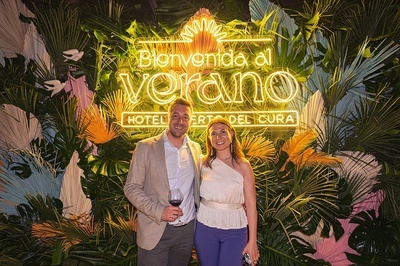 a man and woman standing in front of a sign that says bienvenido al verano - 