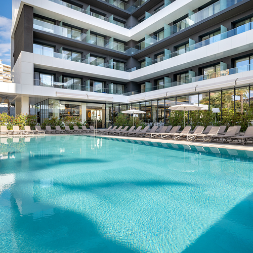 una piscina rodeada de sillas y sombrillas en un hotel