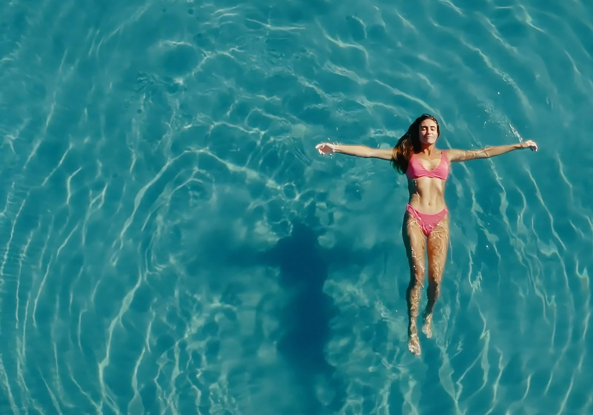 a woman in a pink bikini is floating in the water
