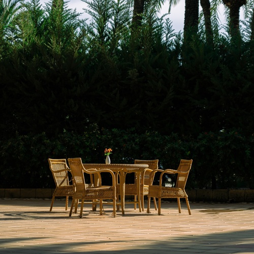 a table and chairs on a wooden deck with palm trees in the background