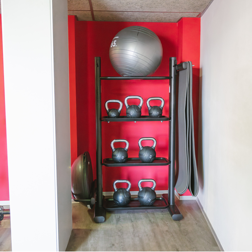 a gym with a spinning bike and a display of kettlebells