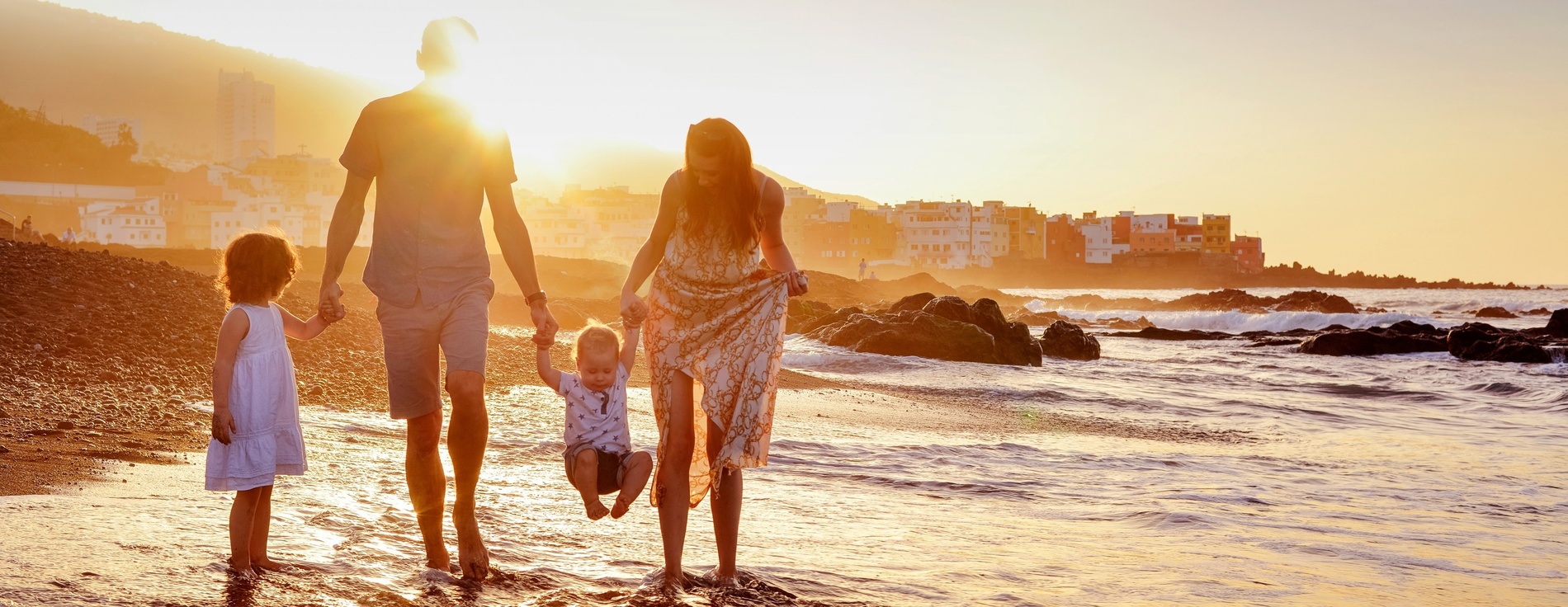 una familia camina por la playa al atardecer