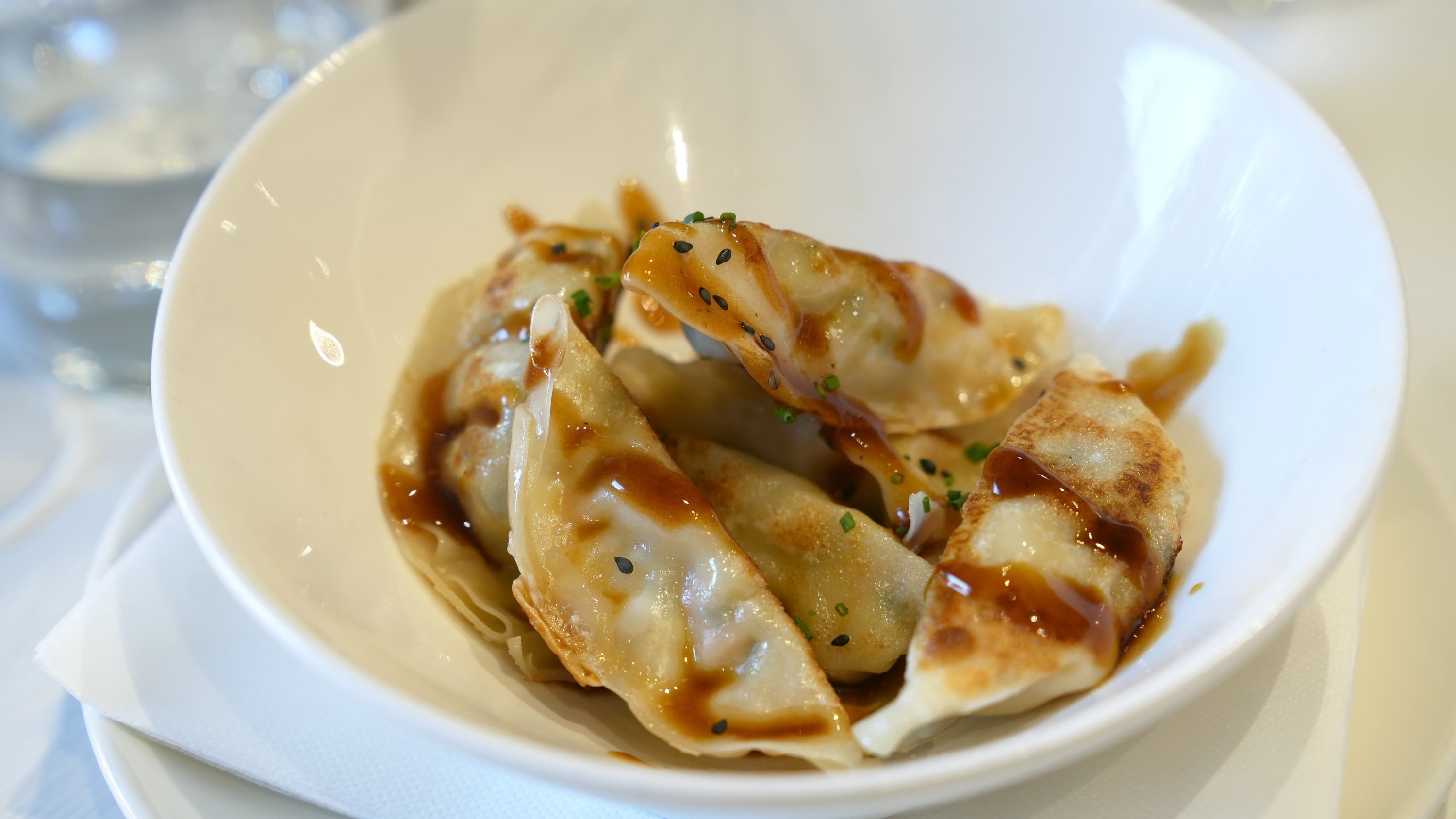 a white bowl filled with fried dumplings and sauce