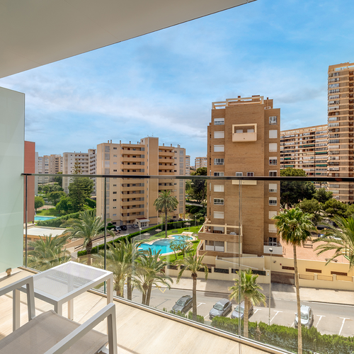 un balcón con dos sillas y una mesa con vistas a un gran edificio