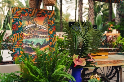 a sign for jamon asado is surrounded by plants - 