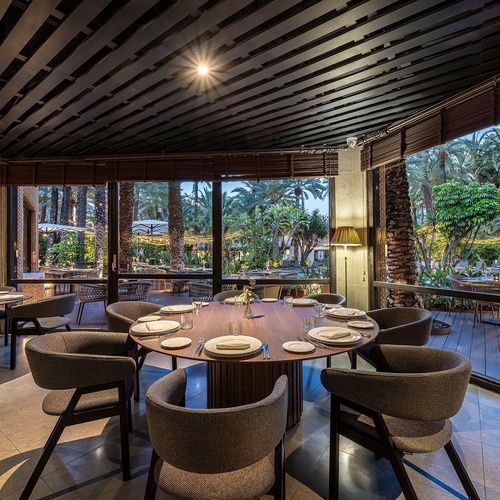 a restaurant with tables and chairs and a view of palm trees