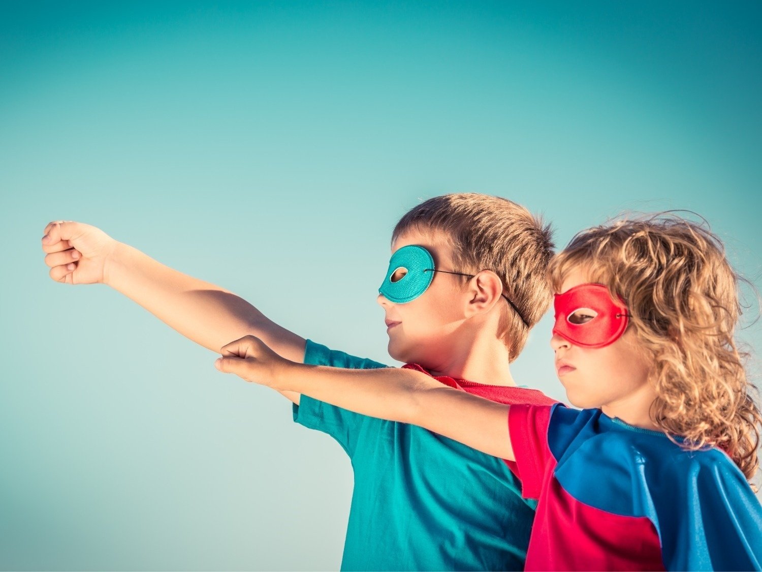 two children wearing superhero costumes with their arms outstretched